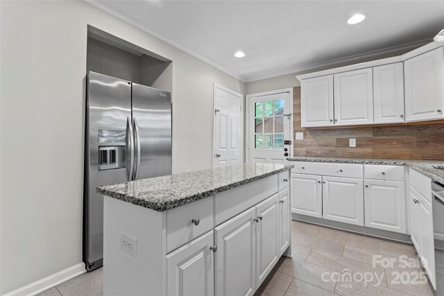 kitchen with stainless steel fridge, ornamental molding, white cabinets, and a kitchen island