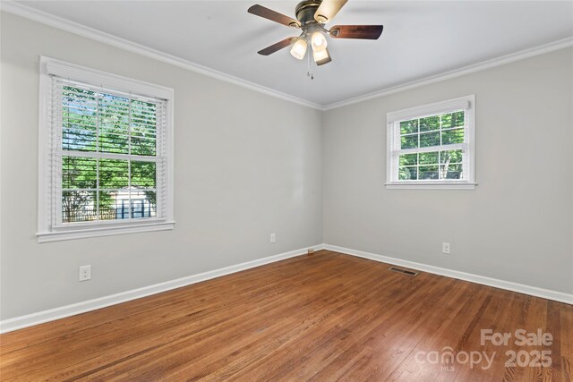 unfurnished room featuring a ceiling fan, visible vents, crown molding, wood finished floors, and baseboards