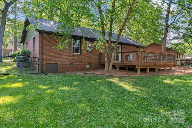 rear view of house with crawl space, a lawn, a deck, a gate, and brick siding