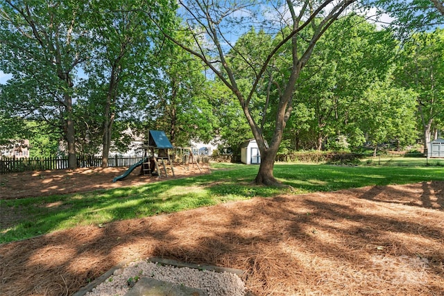 view of yard featuring a playground, a storage unit, an outdoor structure, and fence