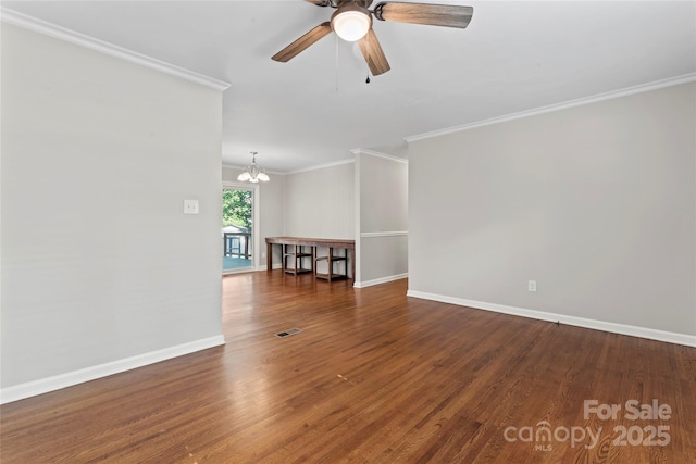 empty room with visible vents, ornamental molding, wood finished floors, baseboards, and ceiling fan with notable chandelier