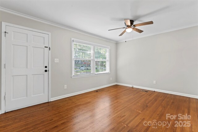 unfurnished room featuring crown molding, visible vents, wood finished floors, baseboards, and a ceiling fan