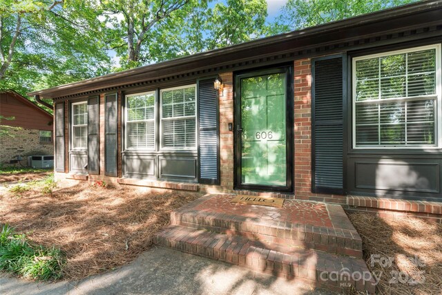 entrance to property with brick siding and central AC