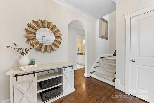 corridor featuring baseboards, arched walkways, stairs, and dark wood-type flooring