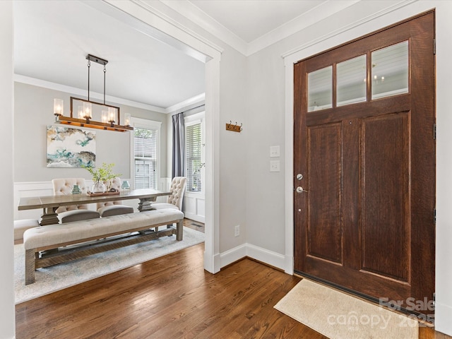 foyer with a chandelier, baseboards, dark wood-style flooring, and crown molding