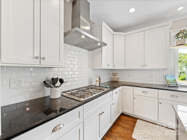 kitchen featuring dark stone countertops, wall chimney exhaust hood, stainless steel gas cooktop, and white cabinets