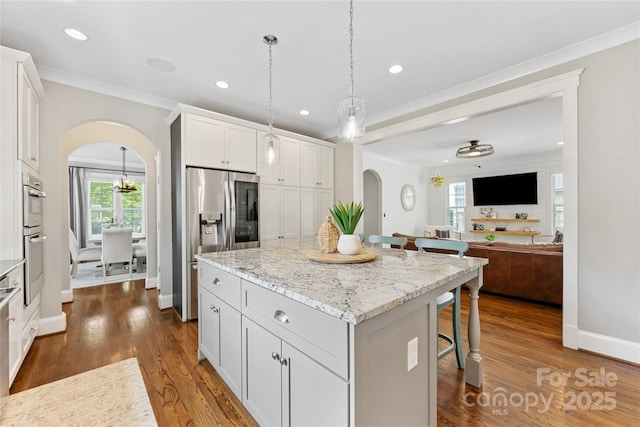 kitchen with a kitchen breakfast bar, a center island, arched walkways, dark wood-style flooring, and stainless steel refrigerator with ice dispenser