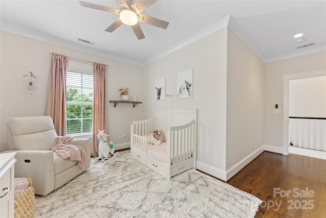 bedroom with crown molding, a ceiling fan, visible vents, baseboards, and wood finished floors