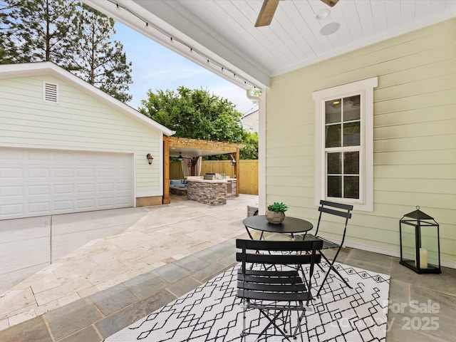 view of patio / terrace with fence, exterior kitchen, ceiling fan, and a garage