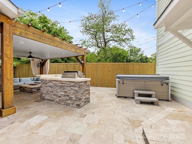view of patio with exterior kitchen, a hot tub, an outdoor fire pit, a fenced backyard, and a grill