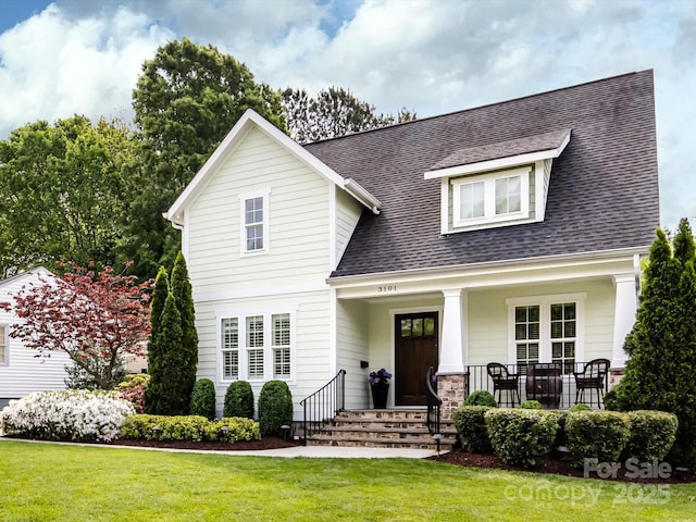 view of front of property with a front lawn, a shingled roof, and covered porch