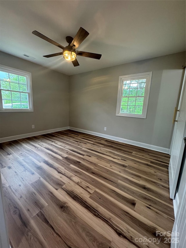 unfurnished room featuring a ceiling fan, baseboards, dark wood finished floors, and visible vents