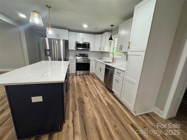 kitchen featuring a sink, appliances with stainless steel finishes, a center island, and wood finished floors