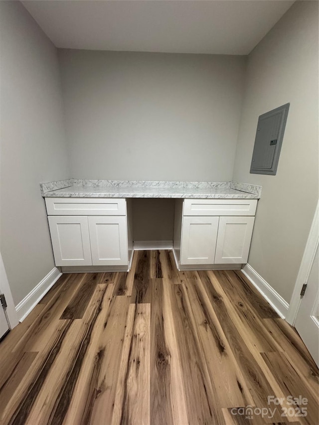 washroom featuring baseboards, electric panel, and wood finished floors