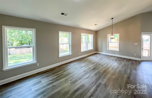 empty room featuring dark wood-style flooring, lofted ceiling, and baseboards