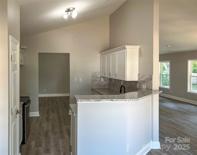 kitchen with light stone countertops, dark wood-style floors, a peninsula, white cabinetry, and electric stove