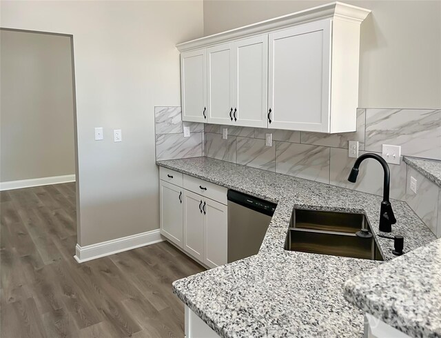 kitchen with dishwasher, a sink, light stone countertops, and backsplash