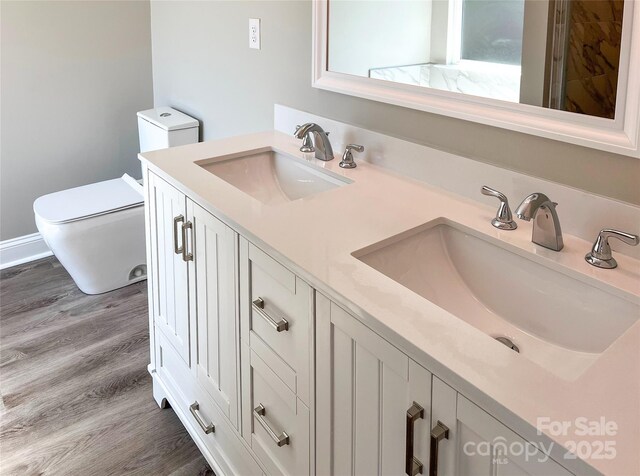 full bath featuring toilet, wood finished floors, and double vanity