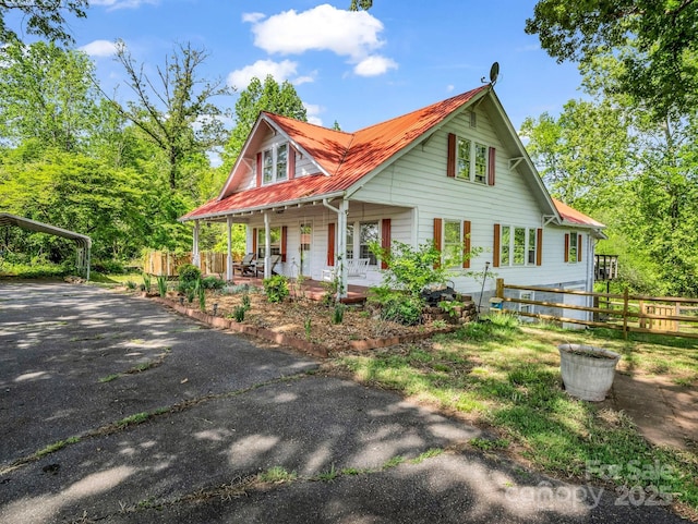 view of front facade featuring fence, aphalt driveway, a porch, a carport, and metal roof