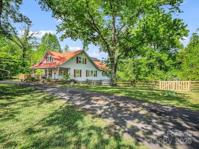 view of front of property featuring a front lawn, fence, covered porch, and driveway