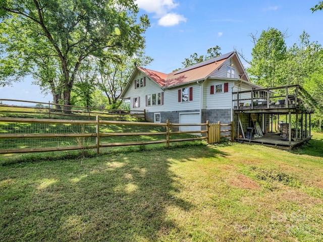 rear view of property featuring fence, an attached garage, a deck, and metal roof