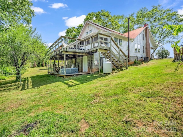 rear view of property featuring a chimney, a lawn, a deck, central air condition unit, and stairs