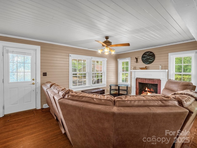living room with ceiling fan, a fireplace, wood walls, and wood finished floors