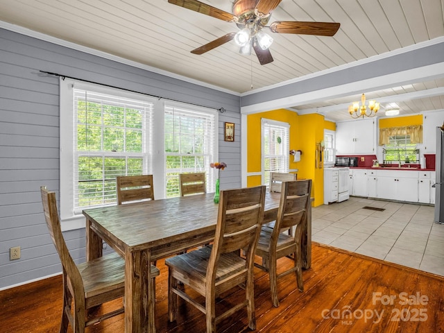 dining area with wood walls, plenty of natural light, wood ceiling, and ceiling fan with notable chandelier