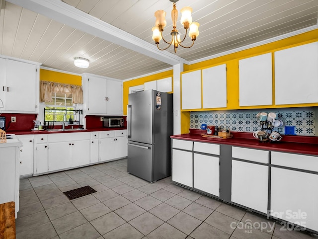 kitchen with backsplash, appliances with stainless steel finishes, a sink, light tile patterned floors, and a chandelier