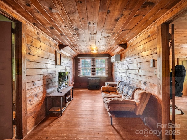 sitting room featuring an AC wall unit, wood ceiling, wooden walls, and vaulted ceiling