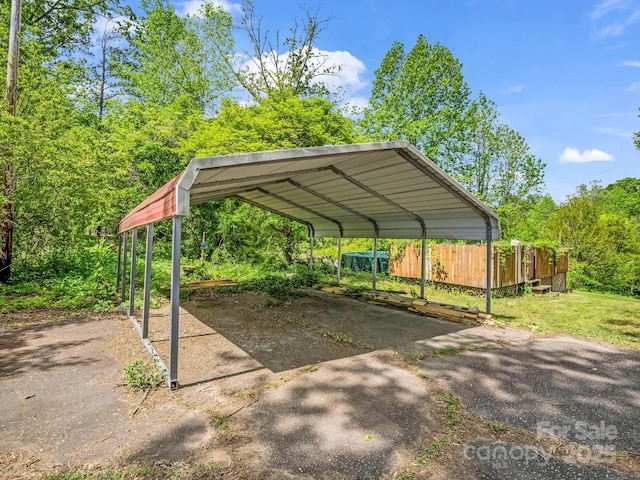 view of parking / parking lot featuring fence and a carport