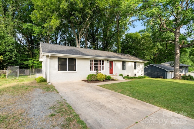 single story home with concrete driveway, brick siding, fence, and a front yard