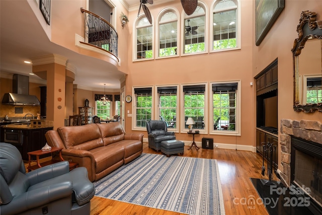 135 Sumter Dr, Mooresville, NC 28117 - living room featuring ornamental molding, a towering ceiling, wood finished floors, a fireplace, and baseboards