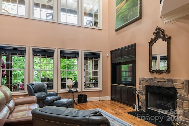 135 Sumter Dr, Mooresville, NC 28117 - living room featuring a stone fireplace, a high ceiling, baseboards, and wood finished floors