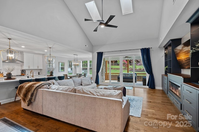 7730 Burning Ridge Dr, Stanley, NC 28164 - living area featuring a chandelier, high vaulted ceiling, wood finished floors, a skylight, and a glass covered fireplace