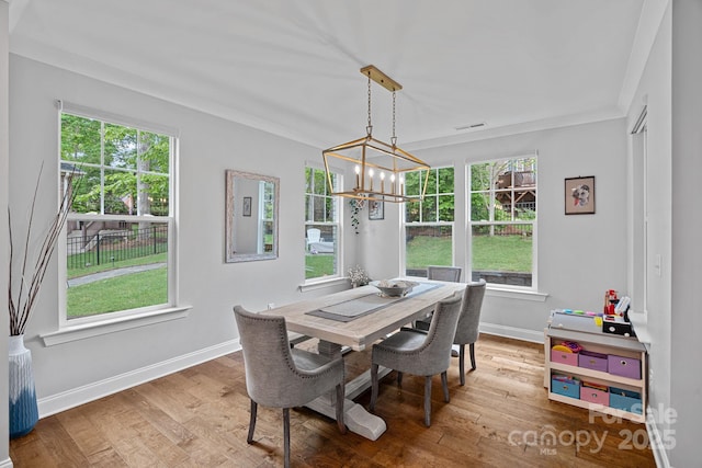 7730 Burning Ridge Dr, Stanley, NC 28164 - dining room featuring wood finished floors, a chandelier, baseboards, plenty of natural light, and crown molding