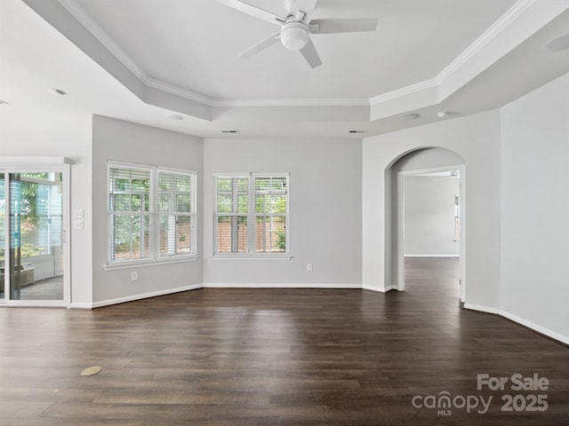 spare room featuring a ceiling fan, arched walkways, a healthy amount of sunlight, and a raised ceiling