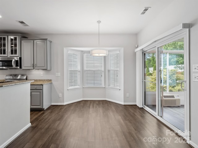 kitchen with stainless steel microwave, dark wood finished floors, glass insert cabinets, and gray cabinets