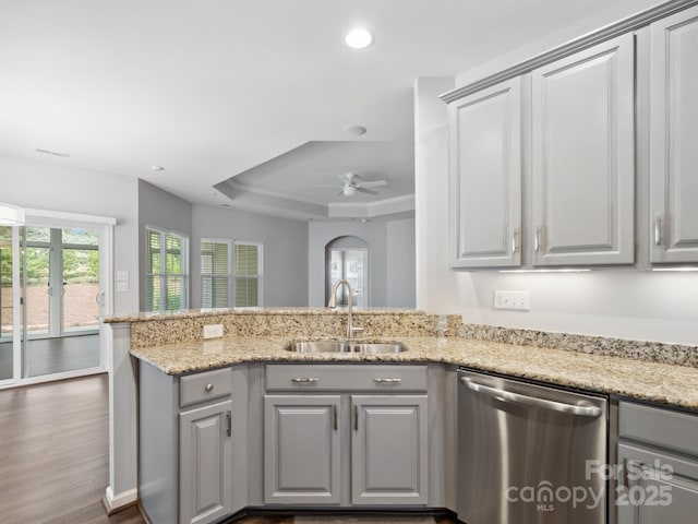 kitchen featuring stainless steel dishwasher, a raised ceiling, a sink, a wealth of natural light, and gray cabinetry