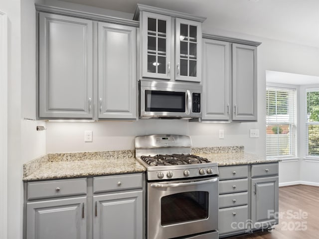 kitchen featuring stainless steel appliances, baseboards, dark wood-type flooring, gray cabinetry, and glass insert cabinets