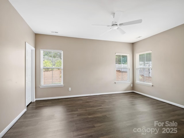 spare room featuring dark wood-type flooring, baseboards, ceiling fan, and visible vents