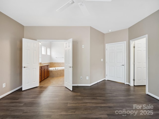 unfurnished bedroom featuring dark wood-type flooring, a ceiling fan, connected bathroom, and baseboards