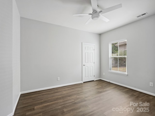 unfurnished room with baseboards, ceiling fan, dark wood-style flooring, and visible vents