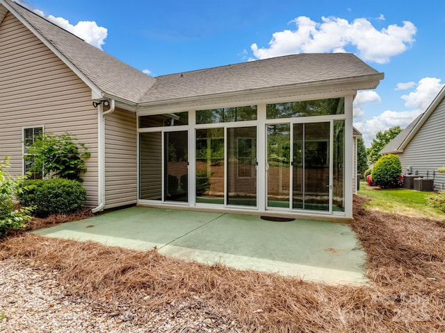 rear view of property featuring a patio, a shingled roof, and central AC unit