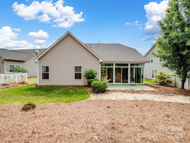 rear view of house with fence, a patio, a sunroom, a shingled roof, and a yard