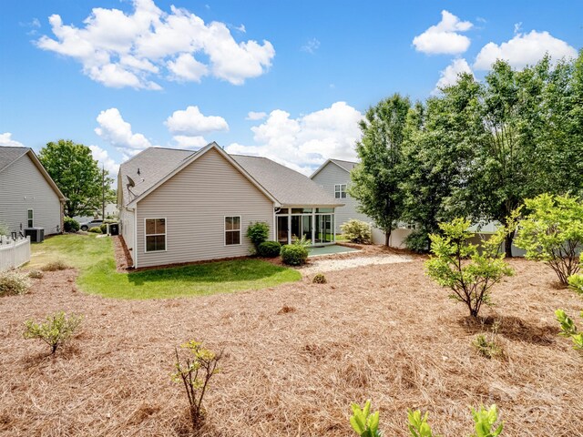 rear view of house featuring central air condition unit, fence, and a sunroom