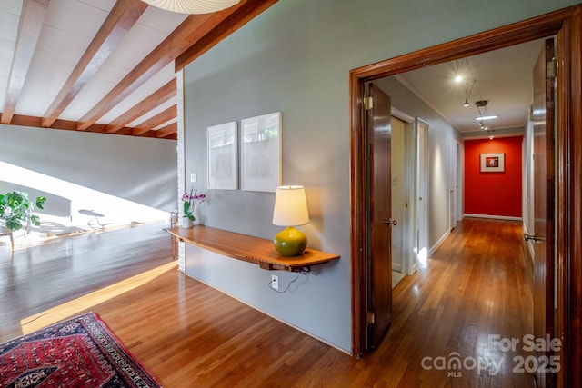 hallway with baseboards, beam ceiling, and wood finished floors