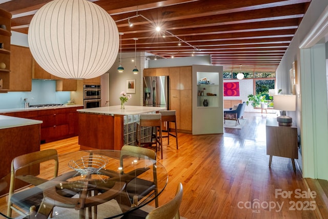 dining room featuring beamed ceiling and light wood finished floors