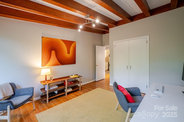 office space with baseboards, light wood-type flooring, and beam ceiling