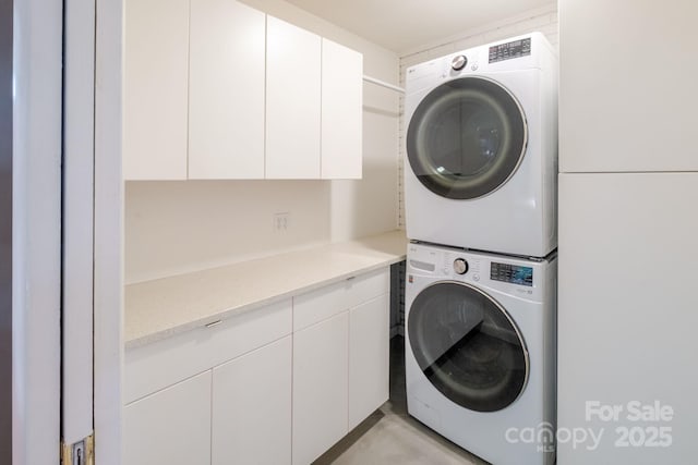 washroom featuring cabinet space and stacked washer and clothes dryer